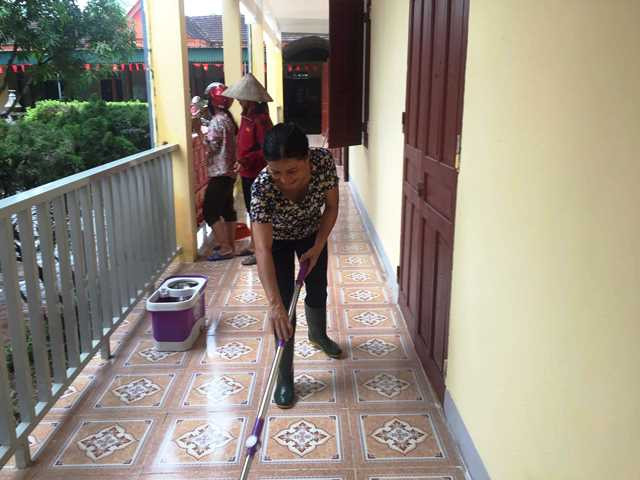 Dùng chổi lau, lau sạch hành lang trường