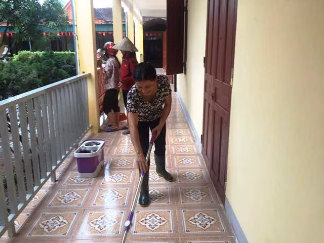 Dùng chổi lau, lau sạch hành lang trường