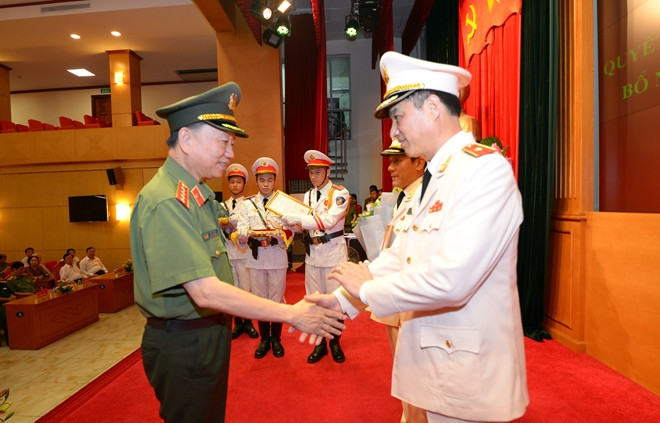 Bộ trưởng Tô Lâm trao quyết định và tặng hoa chúc mừng tân Thứ trưởng Nguyễn Duy Ngọc.