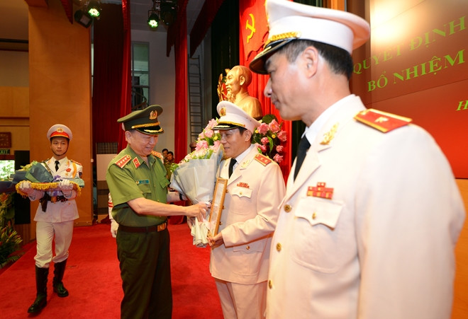 Bộ trưởng Tô Lâm trao quyết định và tặng hoa chúc mừng tân Thứ trưởng Lương Tam Quang.