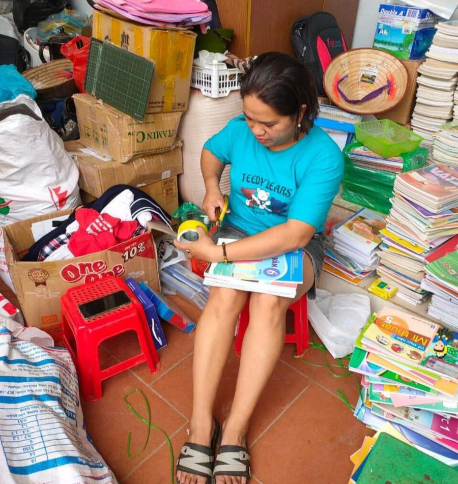 Cô Thủy tỉ mẩn dán những bìa sách bị rách.