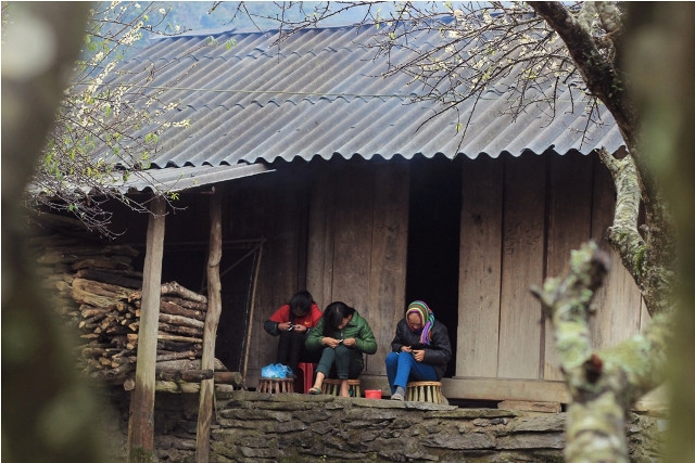 Ba mẹ con đang ngồi thêu váy áo chuẩn bị cho tết