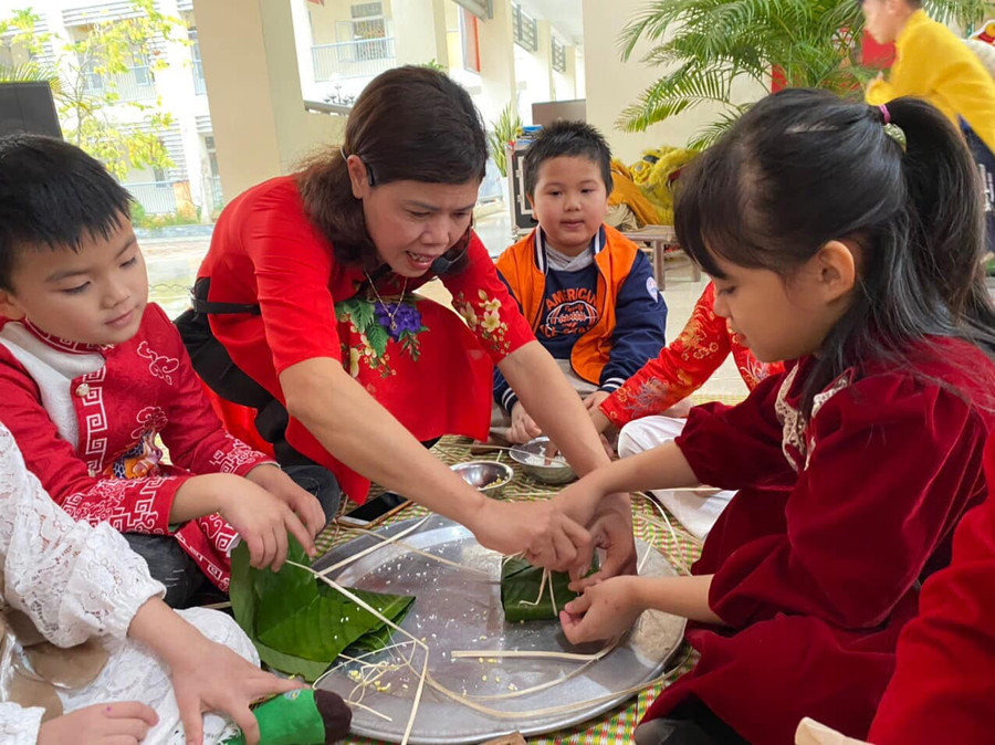 Cô giáo hướng dẫn học sinh cách gói bánh chưng. Cô giáo hướng dẫn học sinh cách gói bánh chưng.