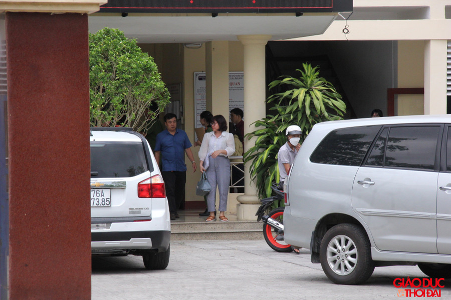 Bà Dung (áo trắng) đi cùng công an rời khỏi trụ sở Văn phòng Đăng ký đất đai tỉnh Quảng Ngãi sáng 27/4.