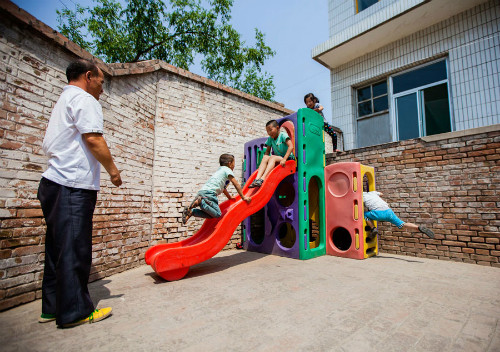 Chen ngắm học sinh chơi đùa ở sân trường. Ảnh:China Daily Chen ngắm học sinh chơi đùa ở sân trường. Ảnh: China Daily