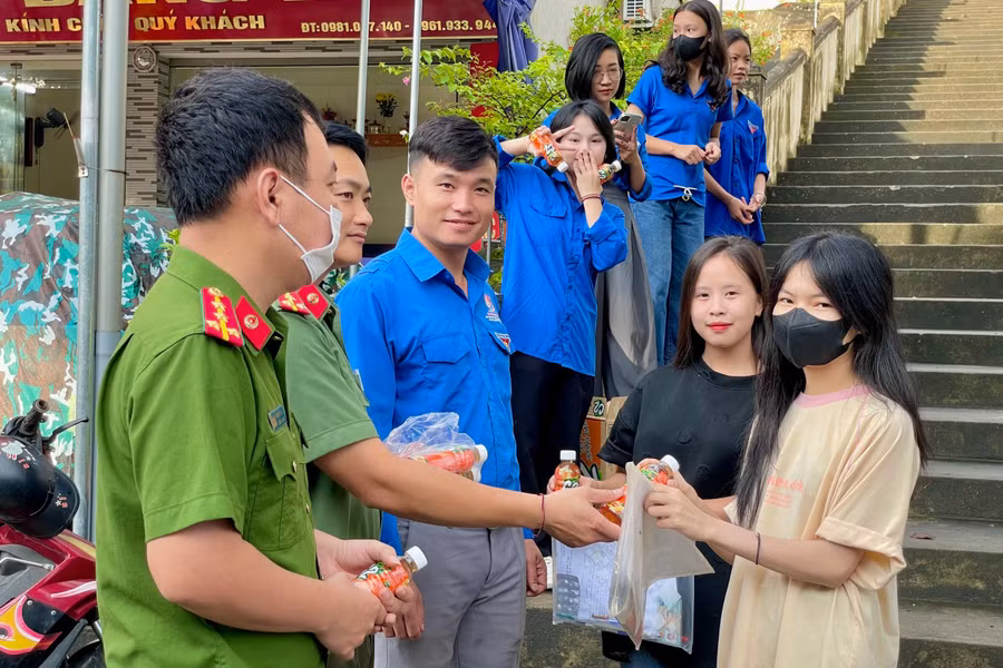 Lực lượng công an, đoàn viên thanh niên hỗ trợ và phát nước cho thí sinh trước điểm thi.