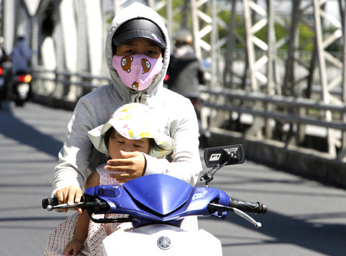 Người phụ nữ chở con gái qua cầu Trường Tiền (Huế) trưa ngày 20/4. Ảnh: Võ Thạnh.