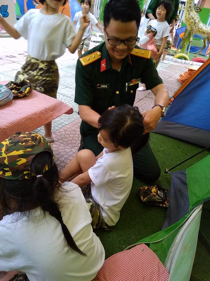 Chú bộ đội buộc tóc cho “chiến sĩ nhí”.