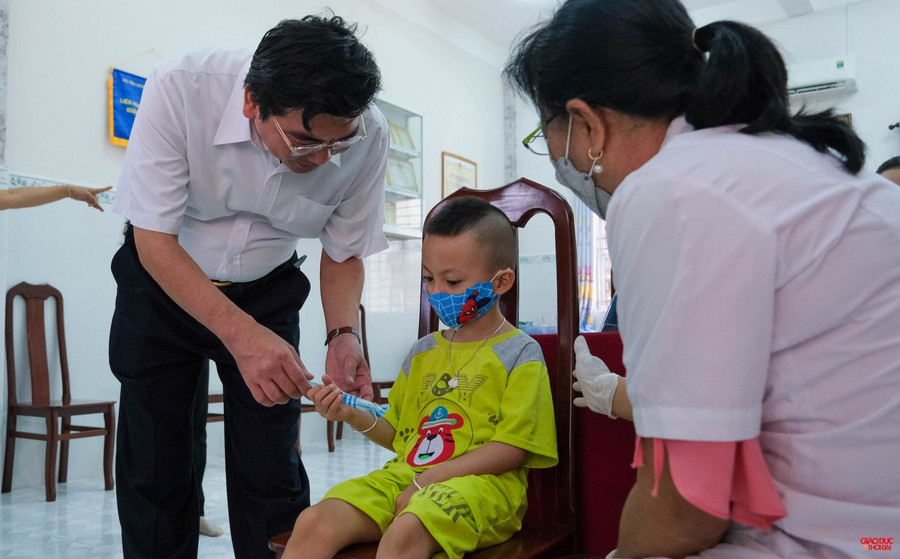 Ông Trần Thanh Bình, Giám đốc Sở GD&ĐT TP Cần Thơ tặng bánh kẹo động viên trẻ sau tiêm ngừa.
