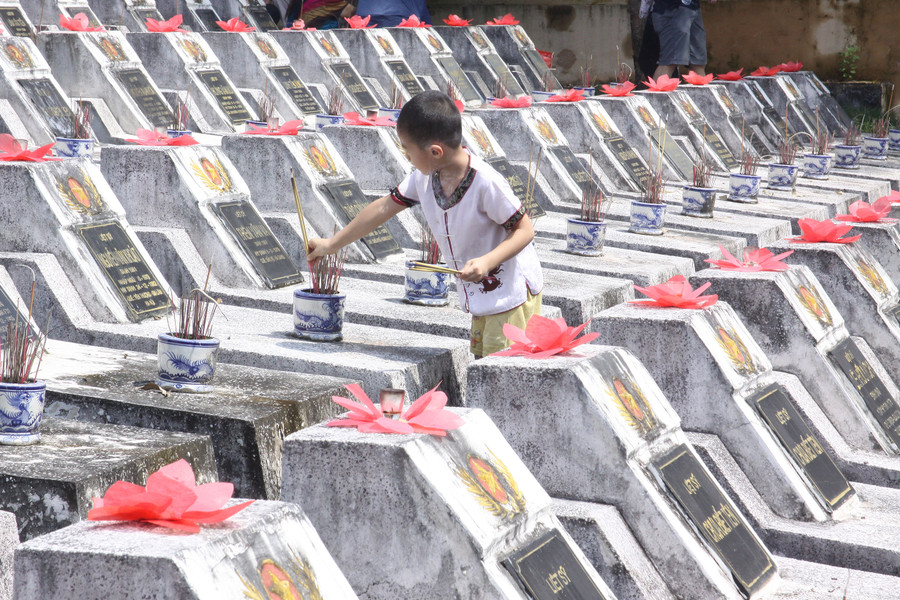 Một em nhỏ đang nén hương cho các chiến sĩ an nghỉ ở Nghĩa trang Vị Xuyên