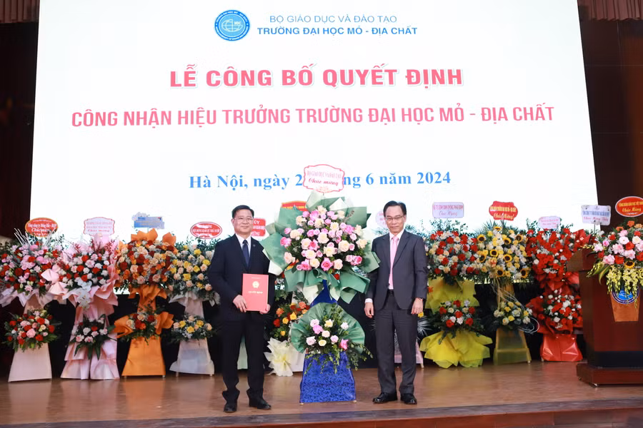 Thứ trưởng Hoàng Minh Sơn (phải) tặng hoa chúc mừng GS.TS Trần Thanh Hải tiếp tục được giữ chức vụ Hiệu trưởng Trường ĐH Mỏ - Địa chất. Ảnh: Đình Tuệ.