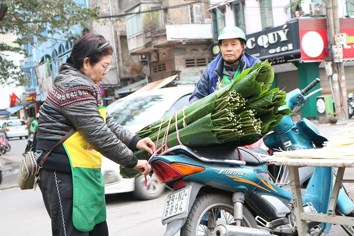 Vội vàng bê chồng lá dong ra cho khách, một tiểu thương chia sẻ: Nhìn chung lá dong trong dịp Tết này bán chạy, chạy hơn cả năm ngoái. Thu nhập của người bán vì thế cũng khá hơn, dù rằng công việc có vất vả.
