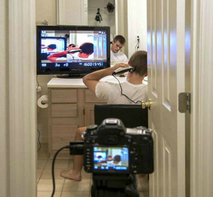 Nhờ chiếc máy ảnh nối với tivi, anh chàng tự cắt tóc đằng saucho mình mà không cần phải ra tiệm.