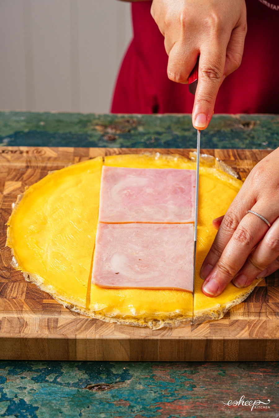 Các “tấm trứng” này bạn xếp chồng lên thớt, đặt luôn 2 miếng jambon vào rồi cắt vừa theo kích cỡ jambon.Lát cuộn cơm các lớp nguyên liệu sẽ rất đều, đẹp.