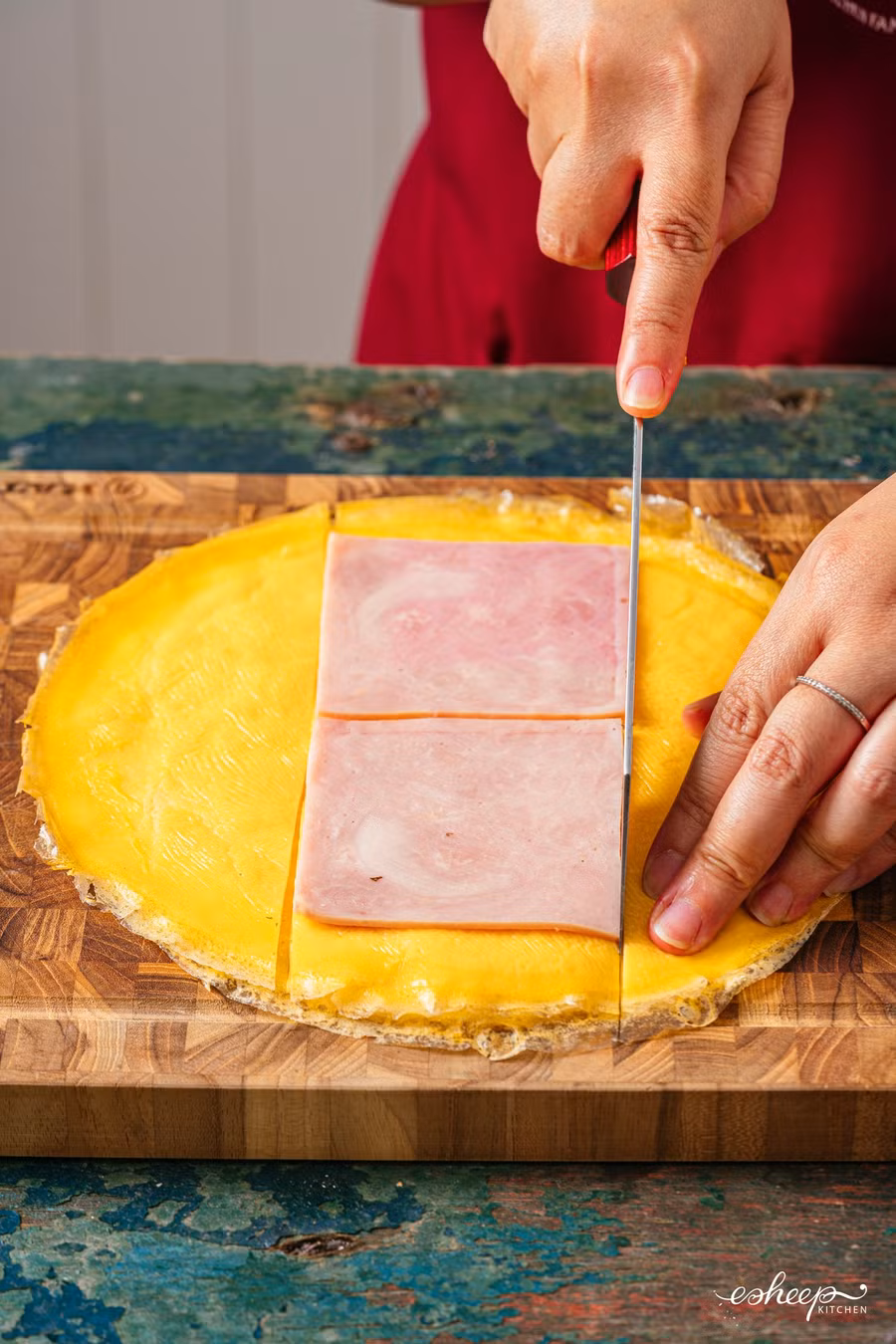 Các “tấm trứng” này bạn xếp chồng lên thớt, đặt luôn 2 miếng jambon vào rồi cắt vừa theo kích cỡ jambon.Lát cuộn cơm các lớp nguyên liệu sẽ rất đều, đẹp.