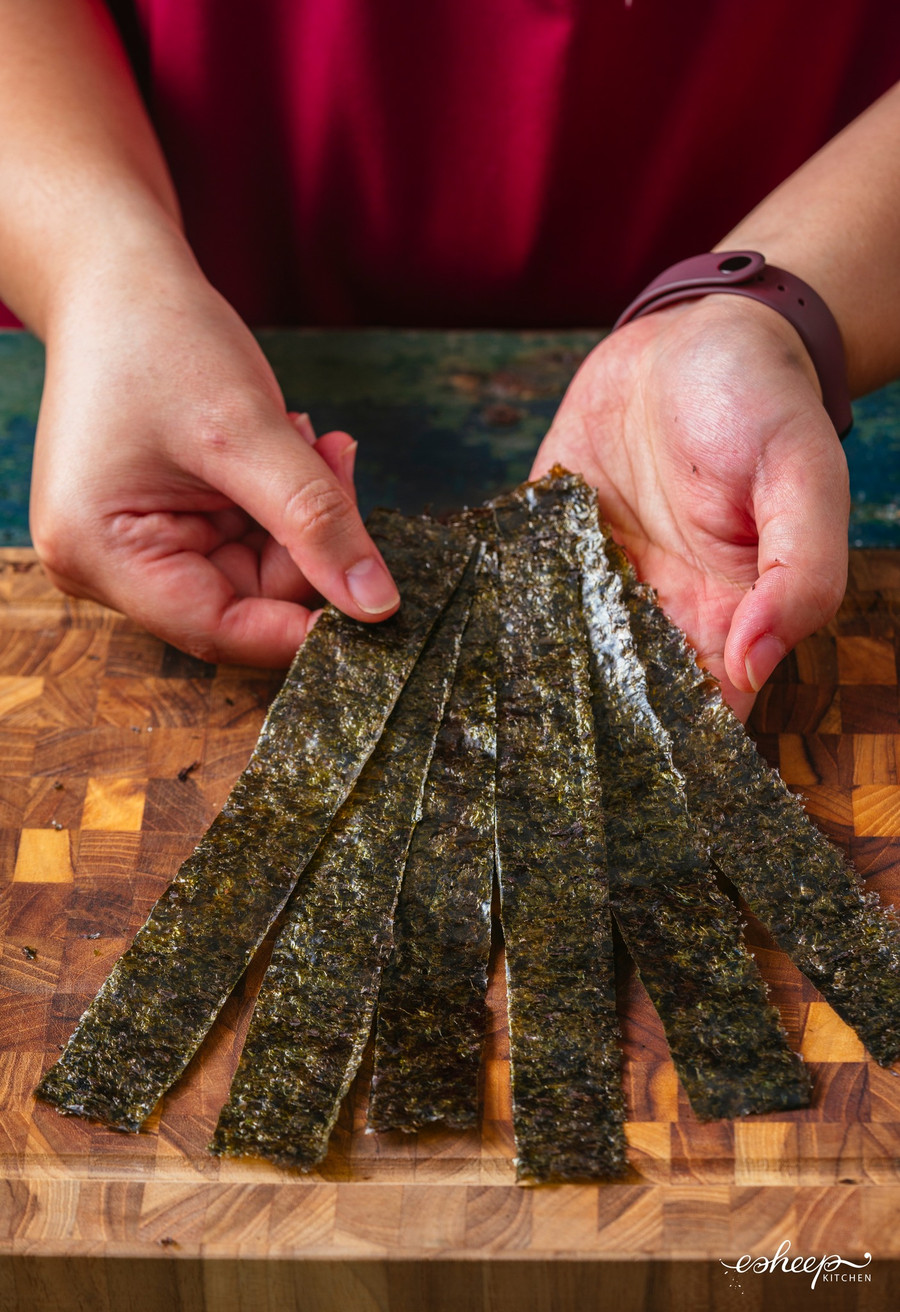 Cắt tấm rong biển cuộn cơm thành các sợi dày chừng 2cm làm “dây nịt” để cố định cuộn cơm.