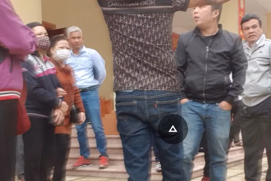 Nhóm đối tượng tập hợp các khách hàng đến tham dự phiên đấu giá lại một chỗ để thông báo về việc người đàn ông tên Toán (mặc áo sơ mi, quần bò, đi giày đỏ, mái tóc bạc) đã "lo hết" và yêu cầu khách hàng không được bỏ giá cao hơn giá khởi điểm là 30 trệu đồng. Ảnh cắt từ clip