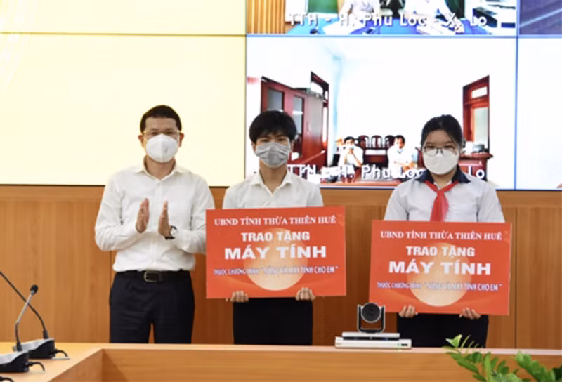 Ông Hoàng Hải Minh - Phó Chủ tịch UBND tỉnh Thừa Thiên Huế trao tượng trưng máy tính tặng cho 2 em học sinh mồ côi cha mẹ do Covid-19. (Ảnh tư liệu)