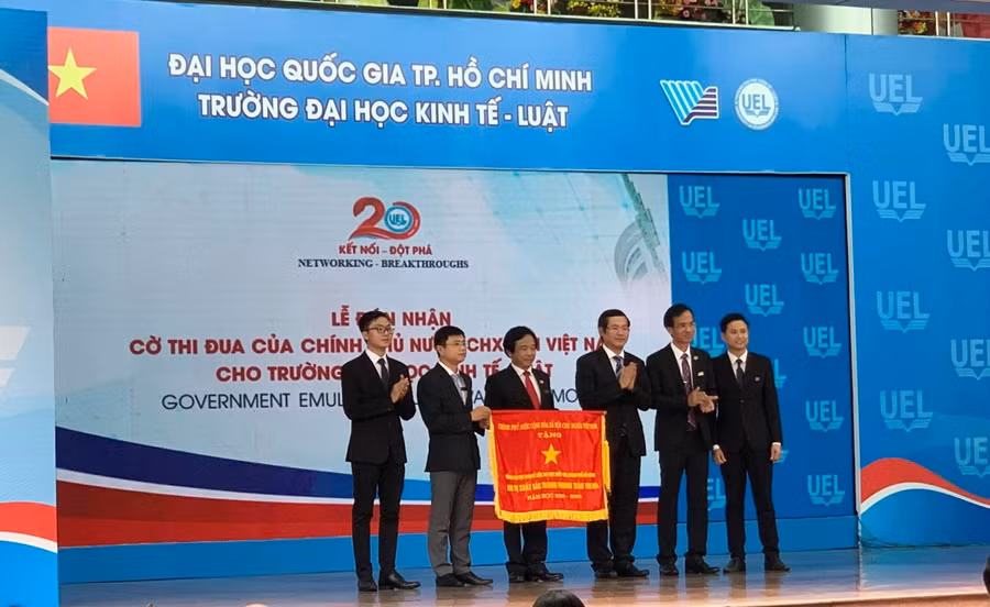 Thứ trưởng Bộ GD&ĐT Nguyễn Văn Phúc (thứ 3 từ phải qua) trao cờ thi đua của Chính phủ tặng Trường ĐH Kinh tế - Luật (ĐHQG TP.HCM)