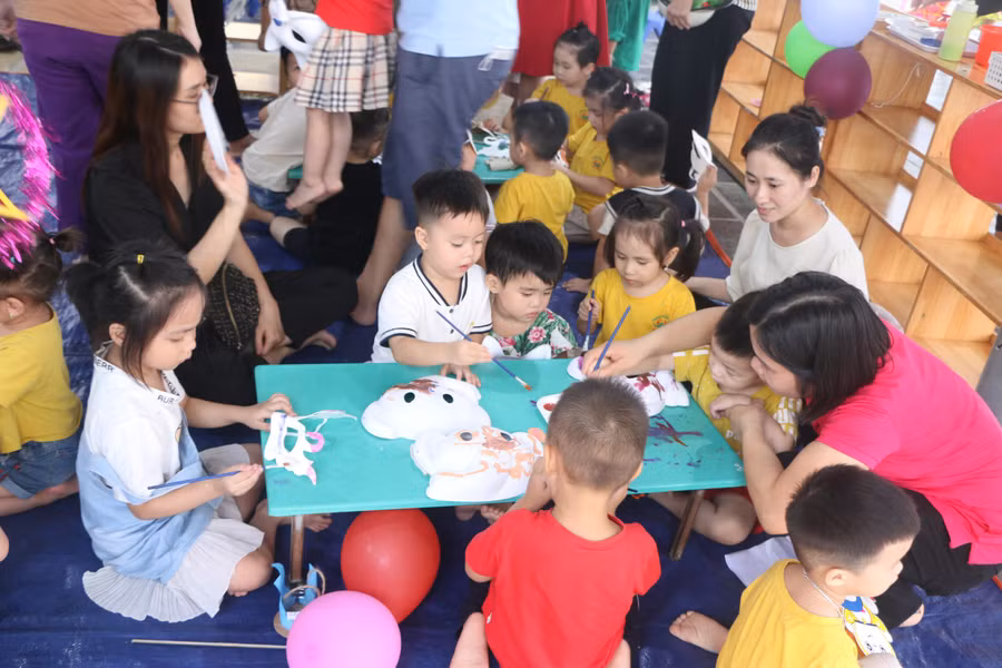 Trẻ được cô giáo và phụ huynh hướng dẫn cụ thể tư thế ngồi và cách tô vẽ mặt nạ.