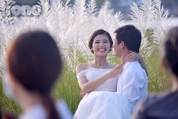 Đôi bạn trẻ ríu rít chụp ảnh cưới, hoạt náo một góc đồng cỏ ở gần cầu Thuận Phước.
