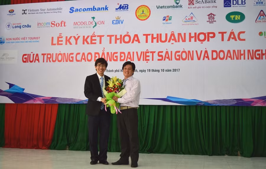 Tiến sĩ Lê Lâm- Hiệu trưởng Trường Cao đẳng Đại Việt Sài Gòn (trái) trao tặng hoa cho đại diện một Doanh nghiệp