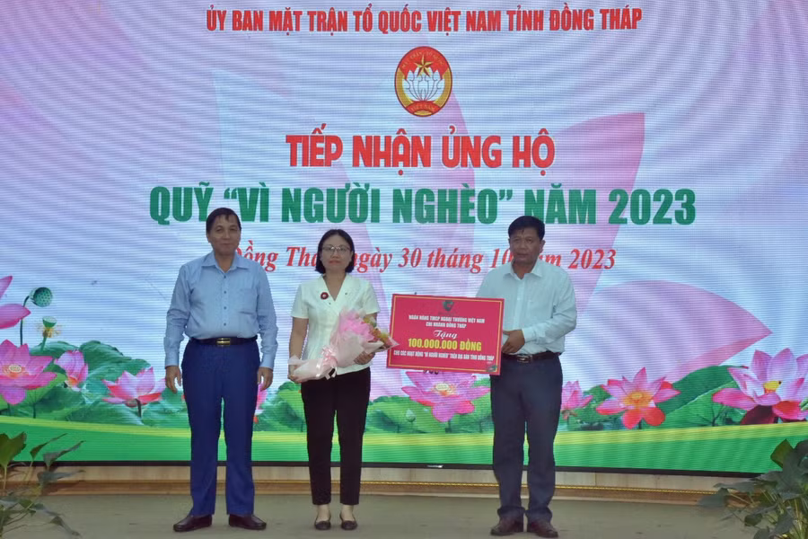 Lãnh đạo tỉnh nhận bảng tượng trưng ủng hộ quỹ "vì người nghèo" từ các nhà tài trợ và tặng hoa cảm ơn.