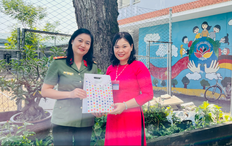 Đại tá Bùi Thị Thanh Liên, Phó Cục trưởng, Cục Hồ sơ Nghiệp vụ - Bộ Công An (bìa trái) trao quà cho bà Lâm Thị Thu Hân, Hiệu trưởng nhà trường.