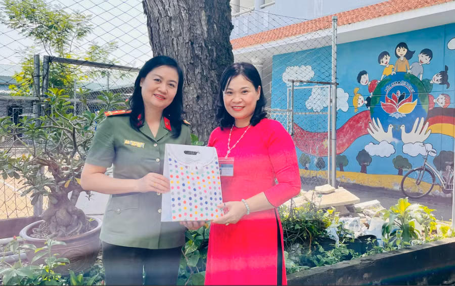 Đại tá Bùi Thị Thanh Liên, Phó Cục trưởng, Cục Hồ sơ Nghiệp vụ - Bộ Công An (bìa trái) trao quà cho bà Lâm Thị Thu Hân, Hiệu trưởng nhà trường.