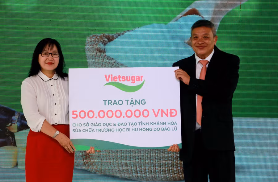 Ông Đỗ Thành Liêm - Tổng Giám đốc Công ty Cổ phần Đường Việt Nam đại diện trao bảng tượng trưng phần quà 500 triệu đồng cho Bà Hoàng Thị Lý – Phó giám đốc Sở Giáo Dục và Đào tạo tỉnh Khánh Hòa nhằm hỗ trợ Sở Giáo dục và Đào tạo tỉnh Khánh Hòa sửa chữa trường học bị hư hỏng do bão lũ.