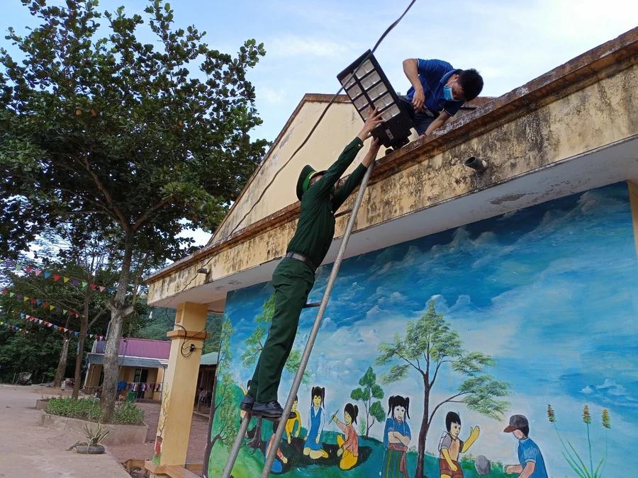 Giáo viên Trường Tiểu học Mỹ Lý 2 và bộ đội Biên phòng lắp đèn năng lượng mặt trời ở khuôn viên sân trường. 