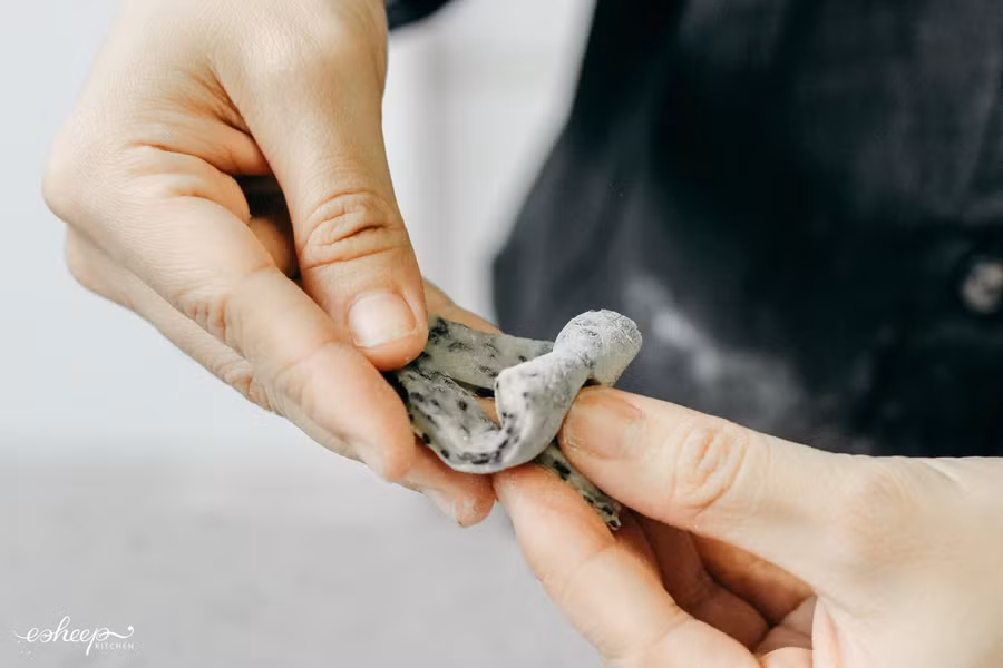 Dùng sự khéo léo của đôi tay để gập bột và thắt lại thành hình nút thắt bùa yêu như hình.