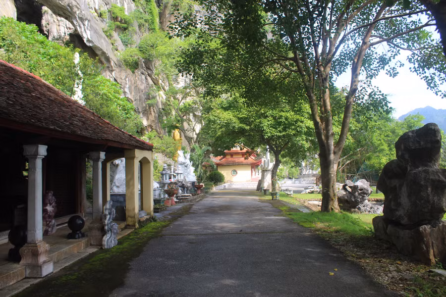 Con đường dẫn vào chùa Linh Ứng rợp bóng mát, bên cạnh là dãy núi đá hùng vĩ. Ảnh: LT.