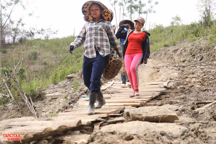 Không đi được xe máy, những người phụ nữ ở bản Nhãn Cù cuốc bộ, leo dốc gùi vật liệu lên bản. Ảnh: Phạm Tâm.