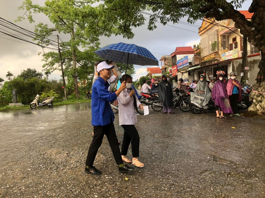 Màu áo xanh tình nguyện che mưa cho thí sinh khi tới điểm thi Trường THPT B Hải Hậu trong sáng 28/6.