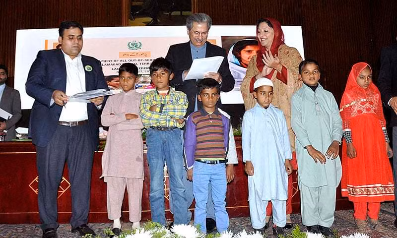 Ông Shafqat Mehmood (đứng giữa, hàng sau) ký vào bản đăng ký học của sáu em nhỏ trong khuôn khổ sự kiện vừa diễn ra