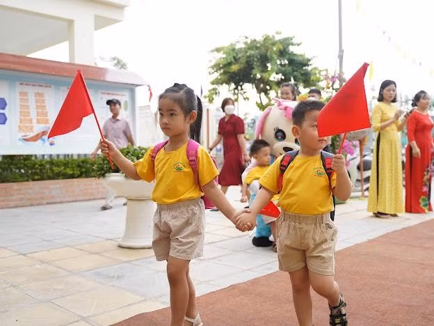 Các bé cùng dắt tay nhau đi vào lớp trong tiếng nhạc hân hoan của buổi khai trường.