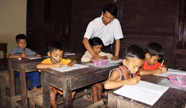 Thầy Trí hướng dẫn cho học sinh Tà Păng viết chữ.