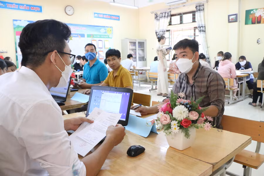 Anh Đinh Văn Vụ (bên phải) đến Trường Tiểu học Vân Canh đã được giáo viên hướng dẫn thủ tục rất nhanh chóng để đăng ký thành công cho con vào lớp 1.