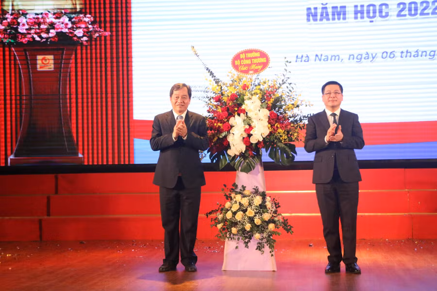 Bộ trưởng Bộ Công thương Nguyễn Hồng Diên (phải) tặng hoa chúc mừng khai giảng năm học mới 2022-2023 cho Trường ĐH Công nghiệp Hà Nội. 