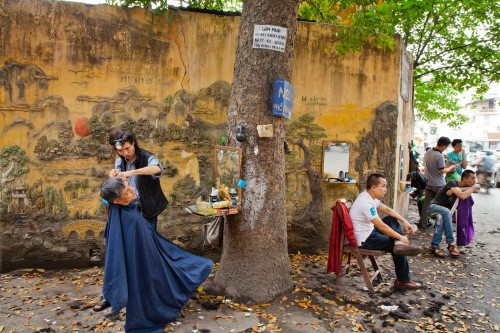 Góc phố với nhiều hàng cắt tóc vỉa hè ở Hà Nội. Góc phố với nhiều hàng cắt tóc vỉa hè ở Hà Nội. Ảnh: Catherine Karnow.