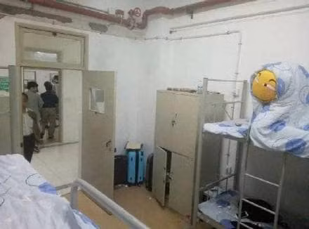 Thầy giáo chủ nhiệm đứng phía ngoài cửa phòng có vẻ hơi bất ngờ với 'sinh vật lạ' đang ngồi trên giường tầng.