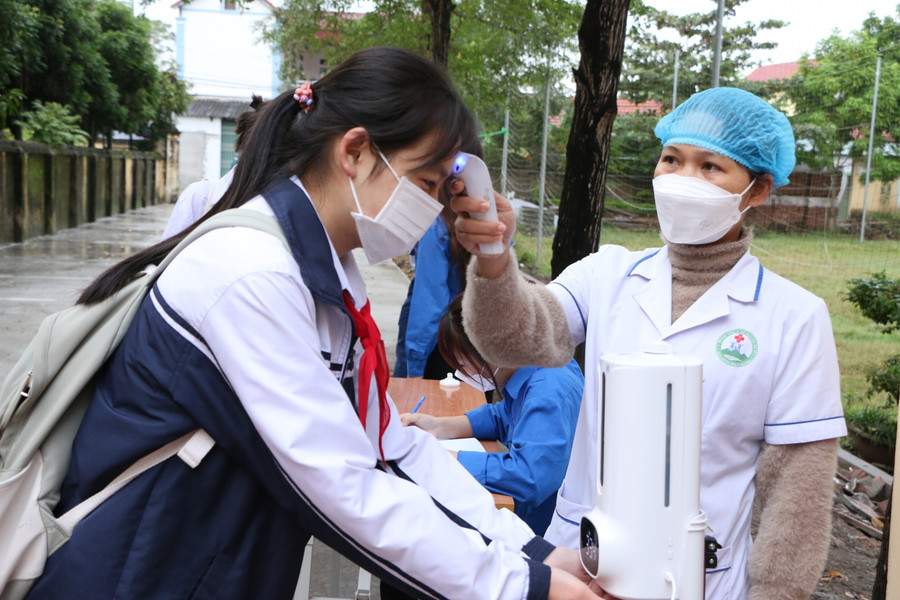 Học sinh Trường THCS Phú Châu được đo thân nhiệt ngay từ cổng trường trước khi vào lớp.