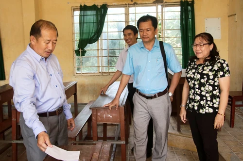 Phó Chủ tịch Uỷ ban nhân dân tỉnh (bìa trái) kiểm tra bàn, ghế tại các phòng thi và lưu ý các điểm thi phải kịp thời sửa chữa, thay mới nếu có bàn, ghế hư hỏng