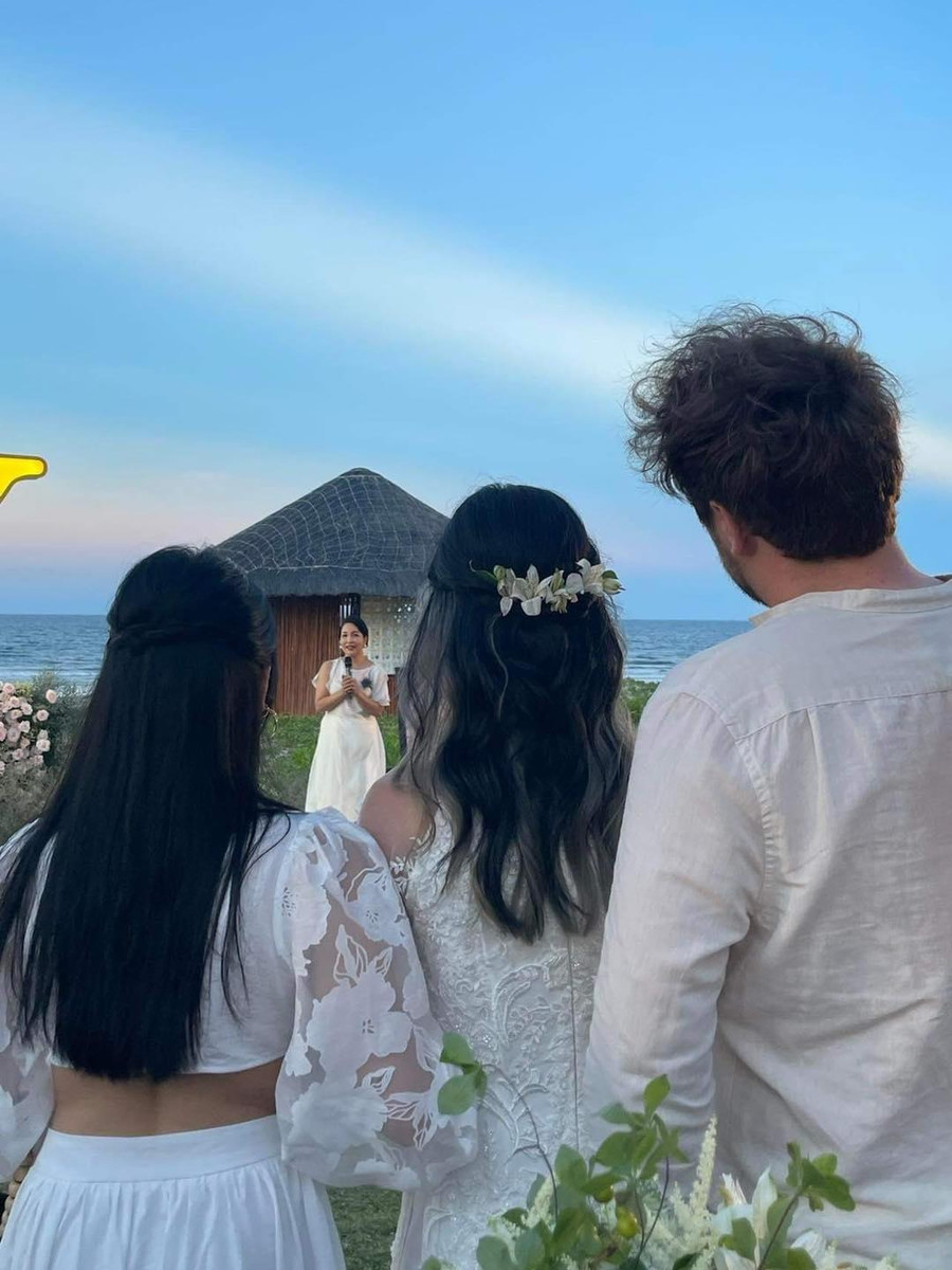 Mỹ Anh đứng cạnh chị gái và hướng mắt về sân khấu nơi mẹ Mỹ Linh đang phát biểu.