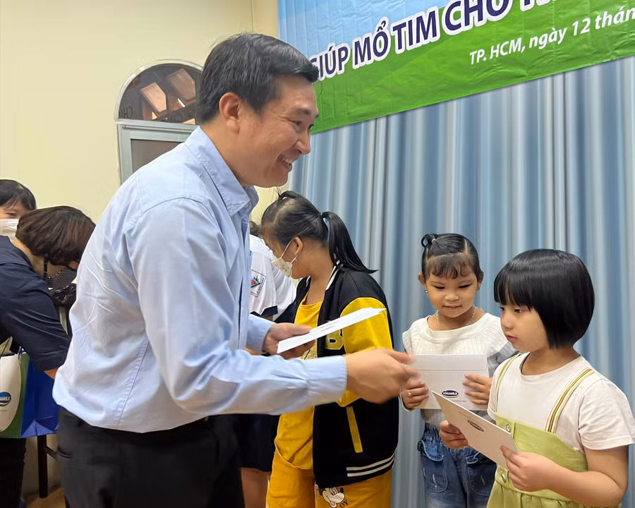 Bé Kỳ Duyên (áo thun trắng, váy xanh) nhận quà động viên từ đại diện công ty Vinamilk.