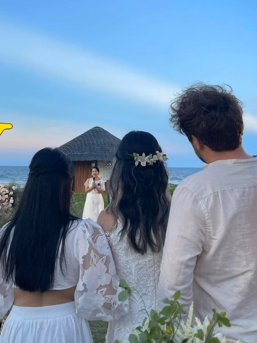 Mỹ Anh đứng cạnh chị gái và hướng mắt về sân khấu nơi mẹ Mỹ Linh đang phát biểu.