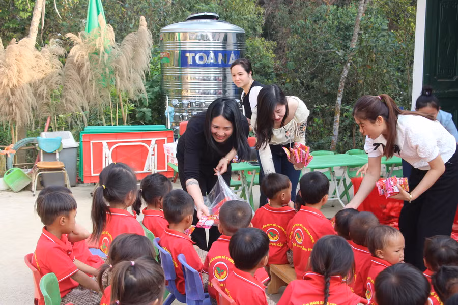 Chị Hoàng Thị Hoa (áo đen) phát quà cho trẻ tại điểm bản Pú Chả.