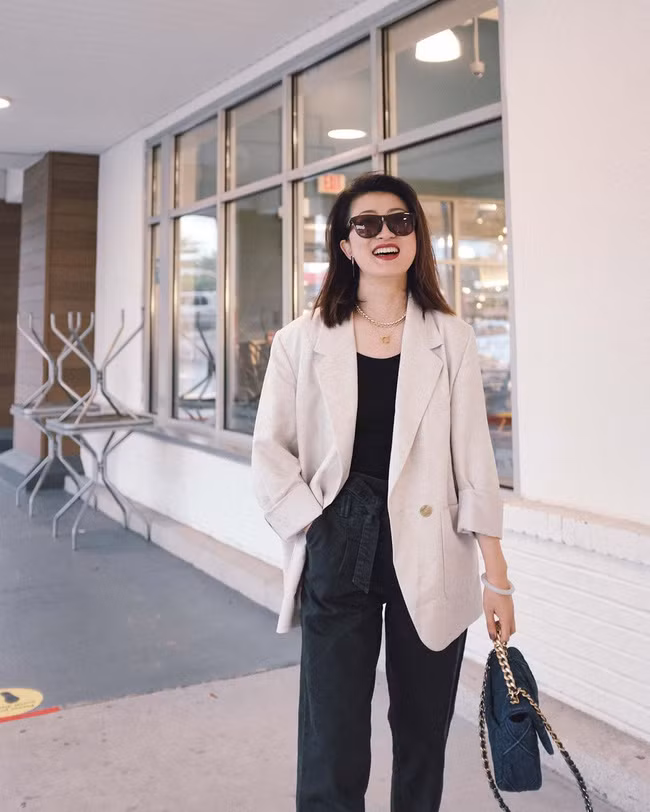 Combo áo thun + quần jeans xuyệt tông đen mix với blazer trắng kem là công thức chị em nên ghim ngay để "quẩy" khi trời chuyển dịu mát. Sự xuất hiện của chiếc blazer sáng màu đã thắp sáng cả set trang phục, giúp vẻ ngoài của người diện thêm trẻ trung nhưng vẫn đủ tinh tế, nhã nhặn.