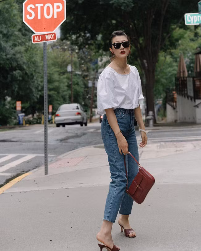 Son môi đỏ trầm, túi xách và sandal xuyệt tông đã giúp cả tổng thể gồm áo blouse trắng + quần jeans ống đứng thêm phần sang xịn, cuốn hút. Những nàng ngoài 30 tuổi càng nên áp dụng tuyệt chiêu này để nâng cấp style công sở.